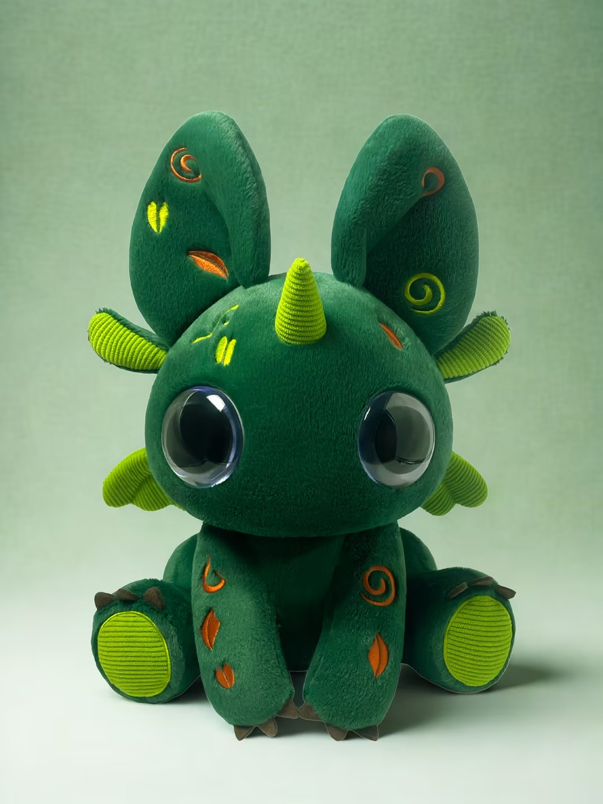 Green plush toy Bloom with large eyes and a small horn on a light green background Skybloom 